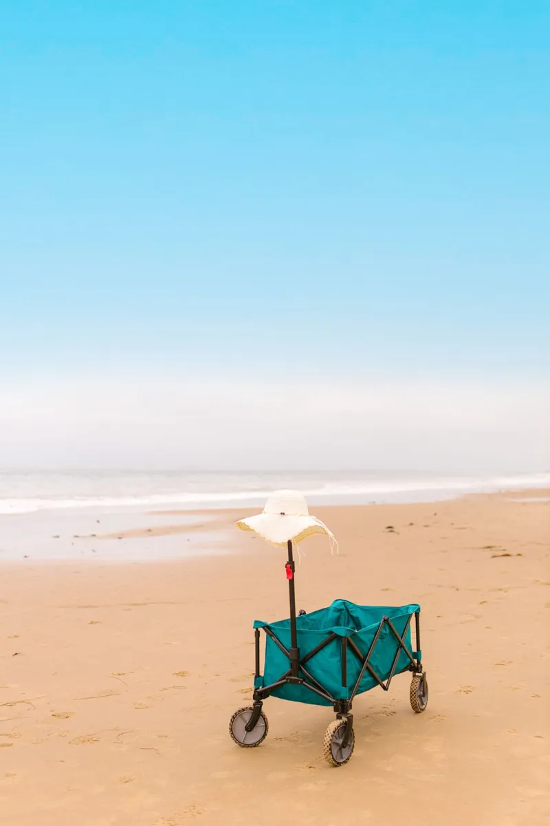 Blue beach cart with a sunhat on a sandy beach