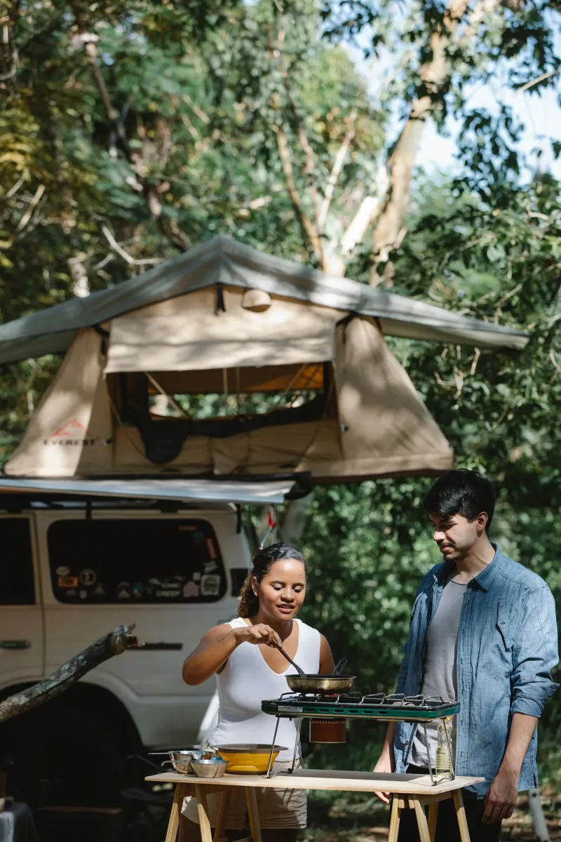 Campers cooking outdoors near their vehicle