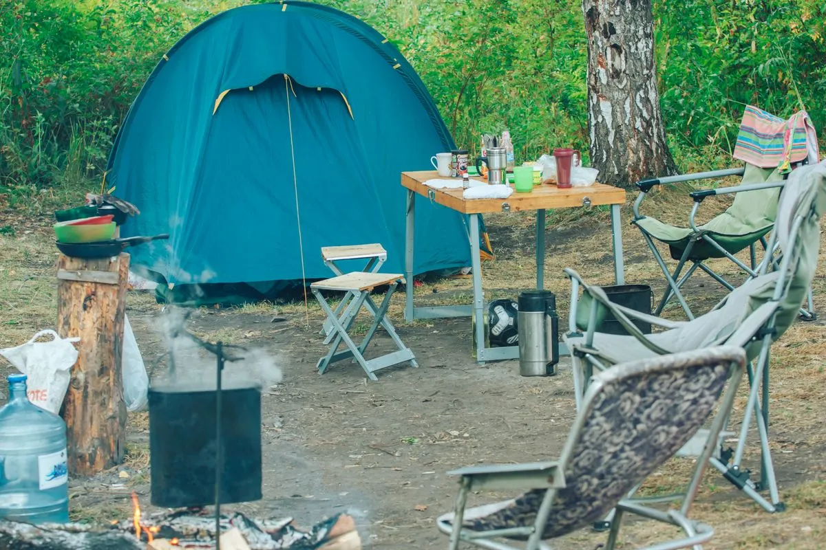 Tent beside camping chairs in a wooded campsite