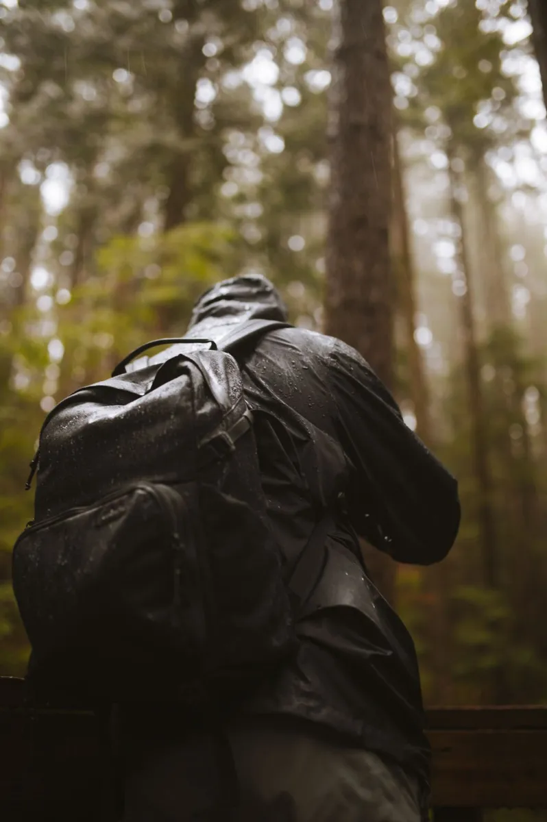 Hiker wearing a hooded jacket and backpack in a forest