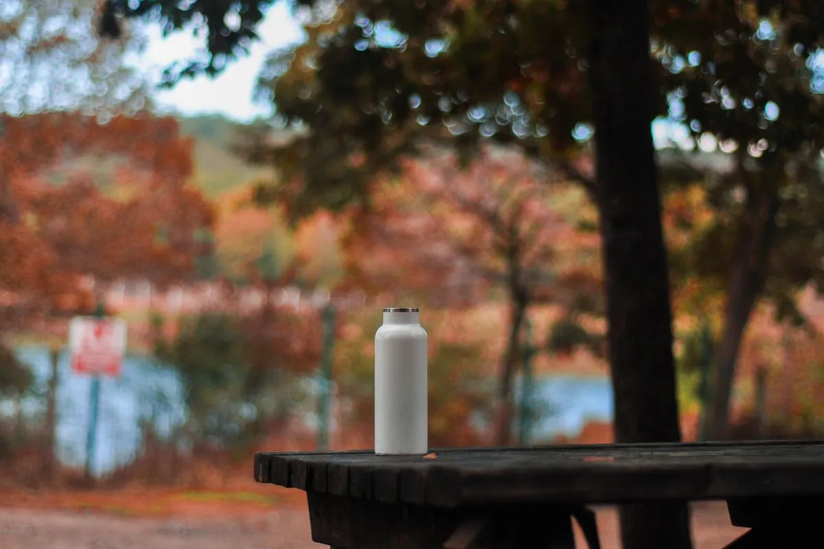 Stainless steel bottle on a picnic table in autumn